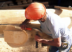 log home builder using a chisel